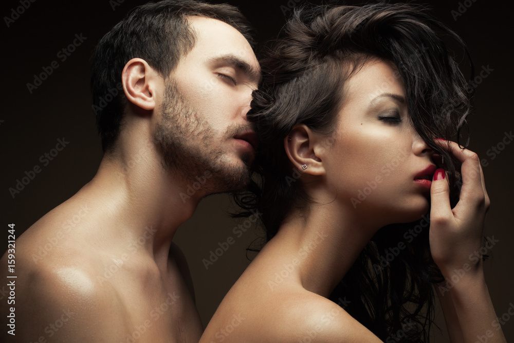 Emotive portrait of two lovers over chocolate background - handsome man and gorgeous woman with perfect hair and skin. Pure passion. Close up. Studio shot