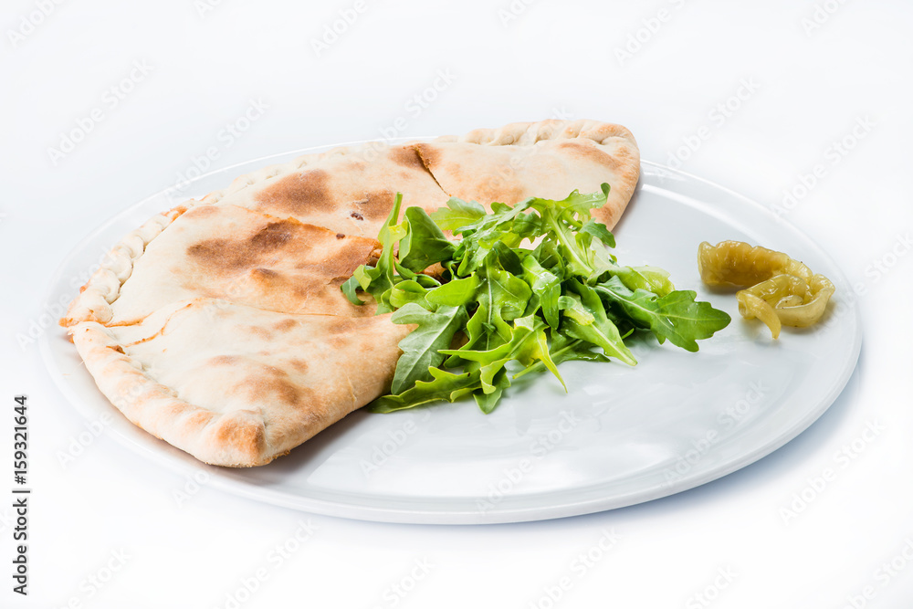 Delicious pizza Calzone on a plate, light background Delicious pizza Calzone on a plate, light background