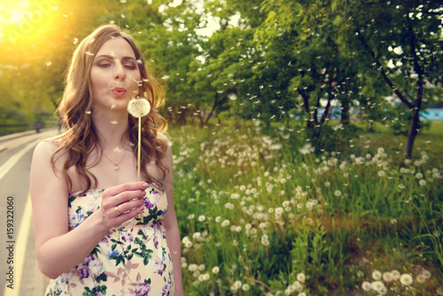 Pregnant young woman blowing dandelion