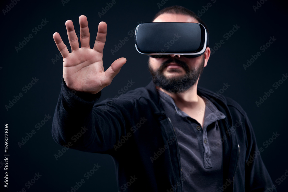 Young hipster bearded man wearing virtual reality goggles. Black background studio VR concept. Young hipster bearded man wearing virtual reality goggles. Black background studio VR concept.