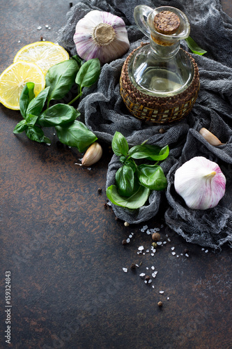 Ingredients for cooking - garlic, lemon, basil, spices and olive oil. Food background on the kitchen table. Copy space.