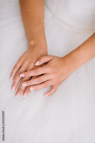 Bride's morning. young beautiful bride in white wedding dress gracefully put hand together. french nail concept.