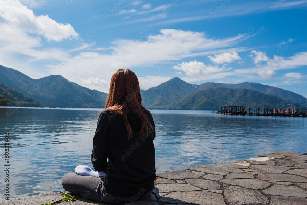 A Woman sitting alone Lake and blue sky background.
