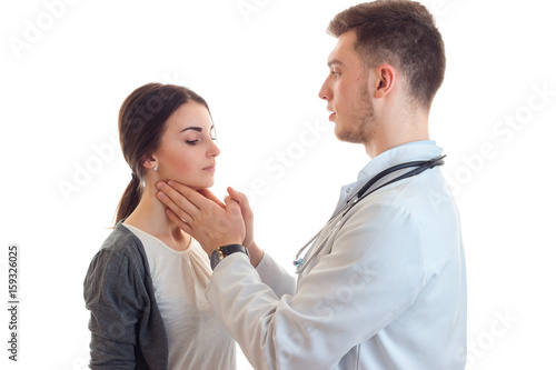 a young girl stands with the doctor and he checks her throat is isolated on a white background