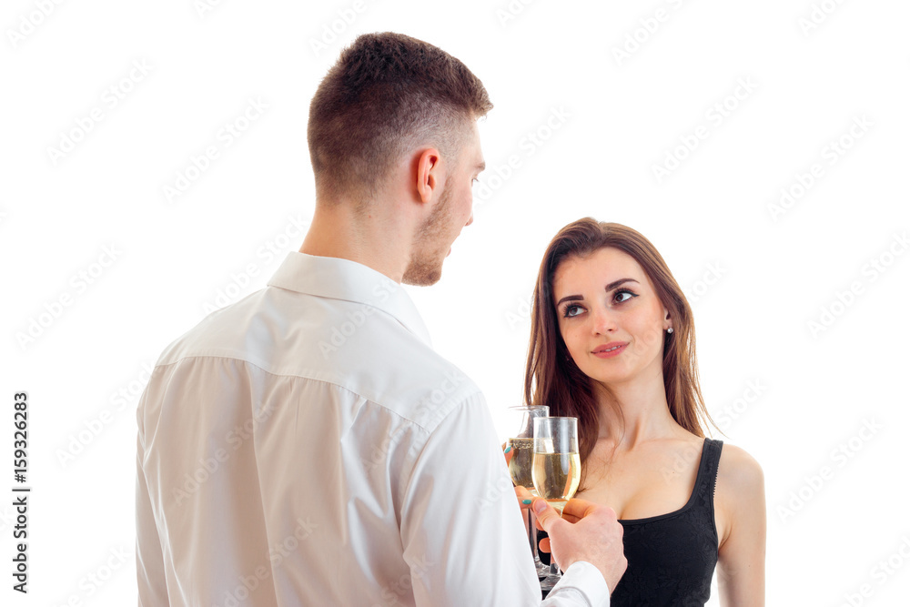 a young guy in a shirt looks at his girl and keeps wine glasses with her isolated on a white background a young guy in a shirt looks at his girl and keeps wine glasses with her isolated on a white background