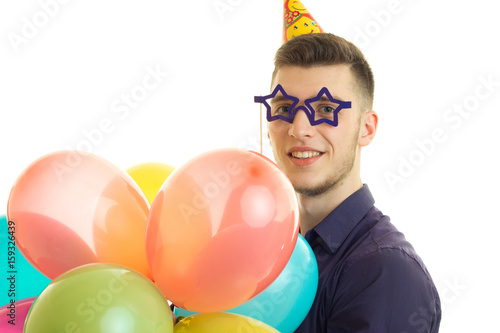 horizontal portrait of beautiful funny guy with glasses in the form of stars and balloons is isolated on a white background © ponomarencko