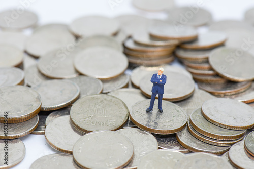 Miniature people: Business man standing on a coins