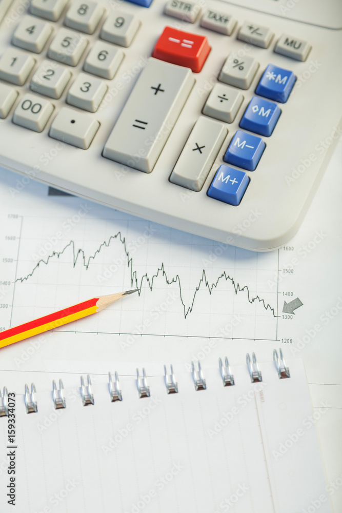 Investment charts with laptop and calculator on wooden table workplace Investment charts with laptop and calculator on wooden table workplace