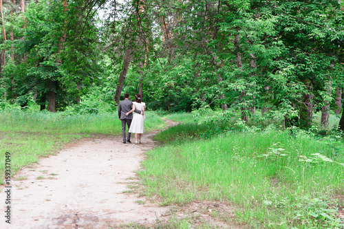 The bride and groom walk in the woods