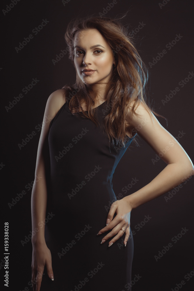 Fashionable brunette young model in black dress with curly hair in motion Fashionable brunette young model in black dress with curly hair in motion