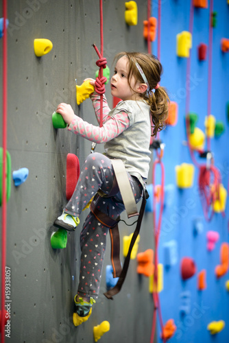 little girl climbing a rock wall indoor