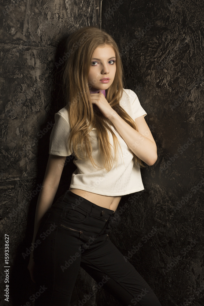 Fototapeta premium Pretty young lady with long blonde hair posing in dark room