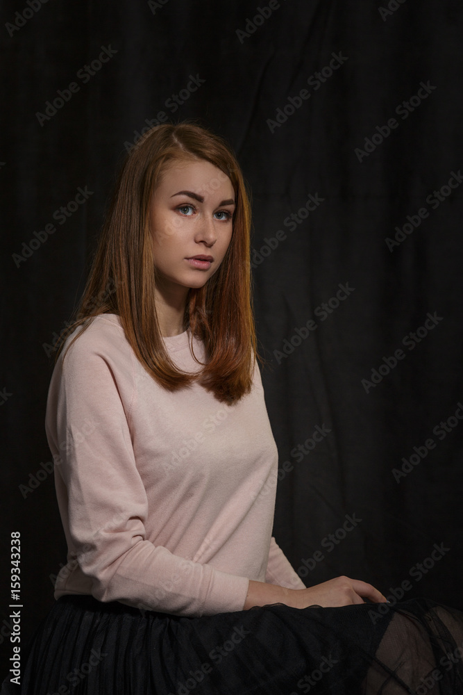 Naklejka premium Portrait of a girl at the age of nineteen on a dark background for advertising