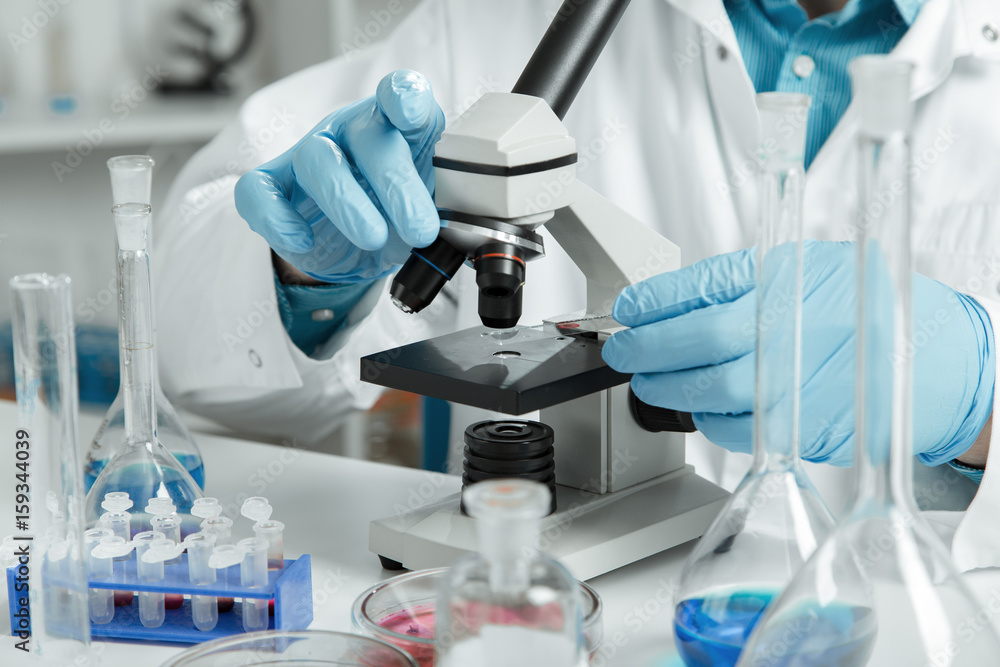 men in a laboratory microscope with microscope slide in hand men in a laboratory microscope with microscope slide in hand