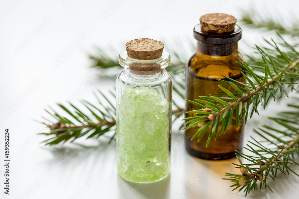 fir branches and spruce bath salt and aroma oil on white table background fir branches and spruce bath salt and aroma oil on white table background