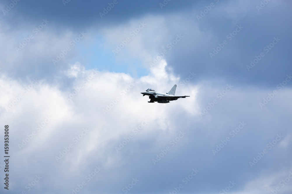 Modern jet fighter flying high in the sky. Dramatic sky with clouds. Modern jet fighter flying high in the sky. Dramatic sky with clouds.
