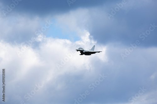 Fototapeta Naklejka Na Ścianę i Meble -  Modern jet fighter flying high in the sky. Dramatic sky with clouds.