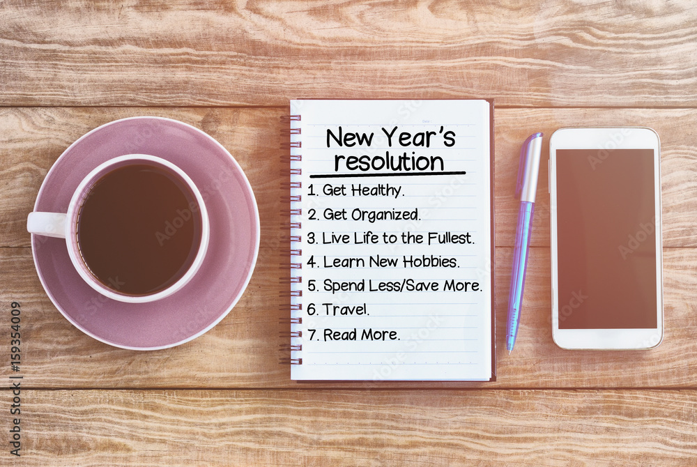 New year's resolution list on note pad, wood table with coffee, pen and smart phone retro styled. New year's resolution list on note pad, wood table with coffee, pen and smart phone retro styled.