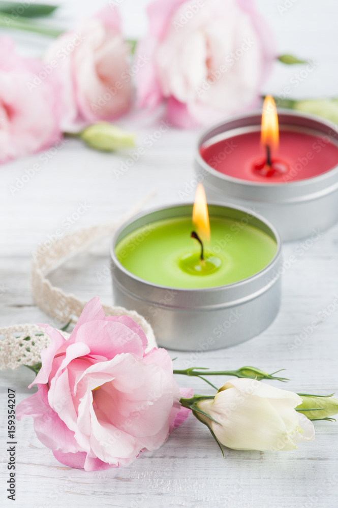 Pink eustomas on a white wooden board, lit candles