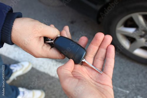 car sales. one person sells car and gives the key to the new owner
