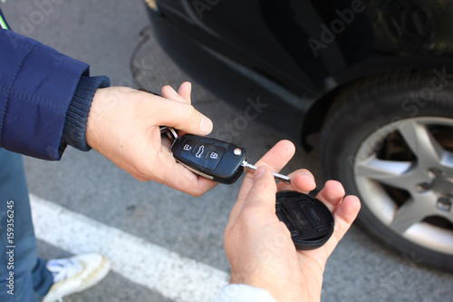 car sales. one person sells car and gives the key to the new owner