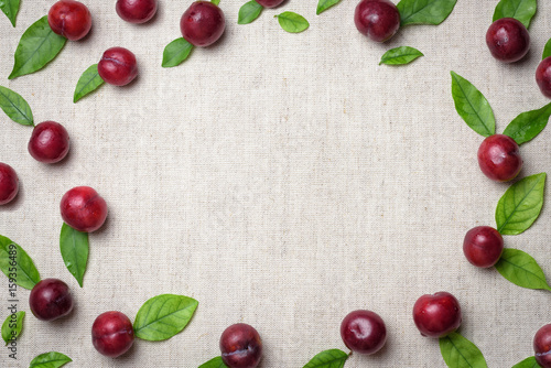 Red sweet cherry berry frame or border. Fresh ripe cherry with green leaves on linen grey background. Top view, copy space