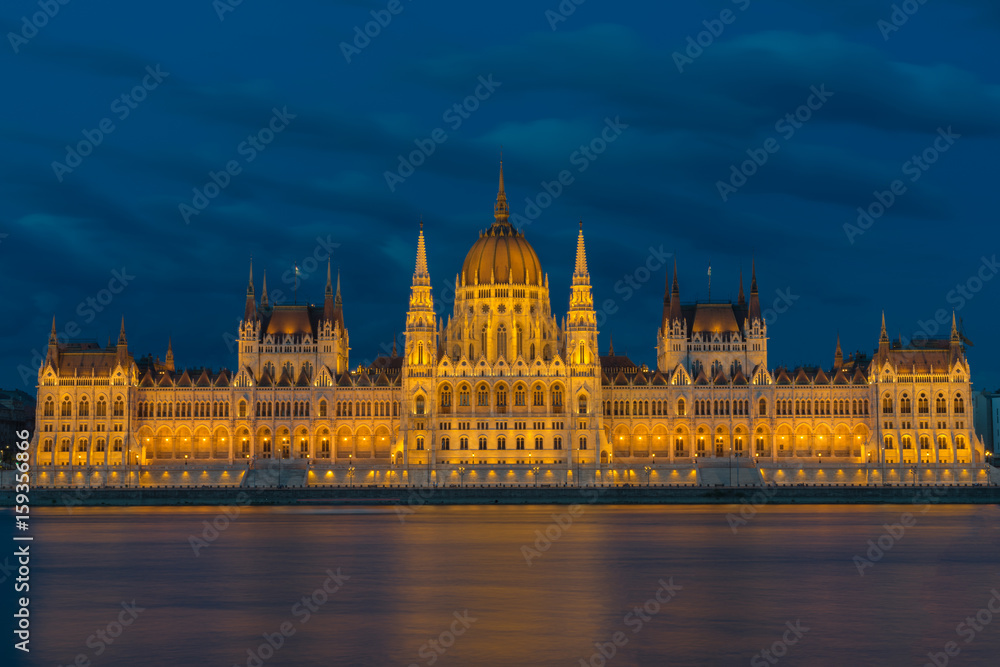 beleuchtetes Parlamentsgebäude in Budapest mit Donau im Vordergrund