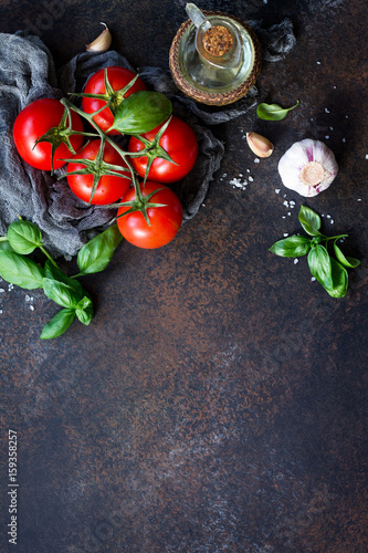 Ingredients for cooking - garlic, tomatoes, basil, spices and olive oil on the kitchen table. Food background. Copy space.