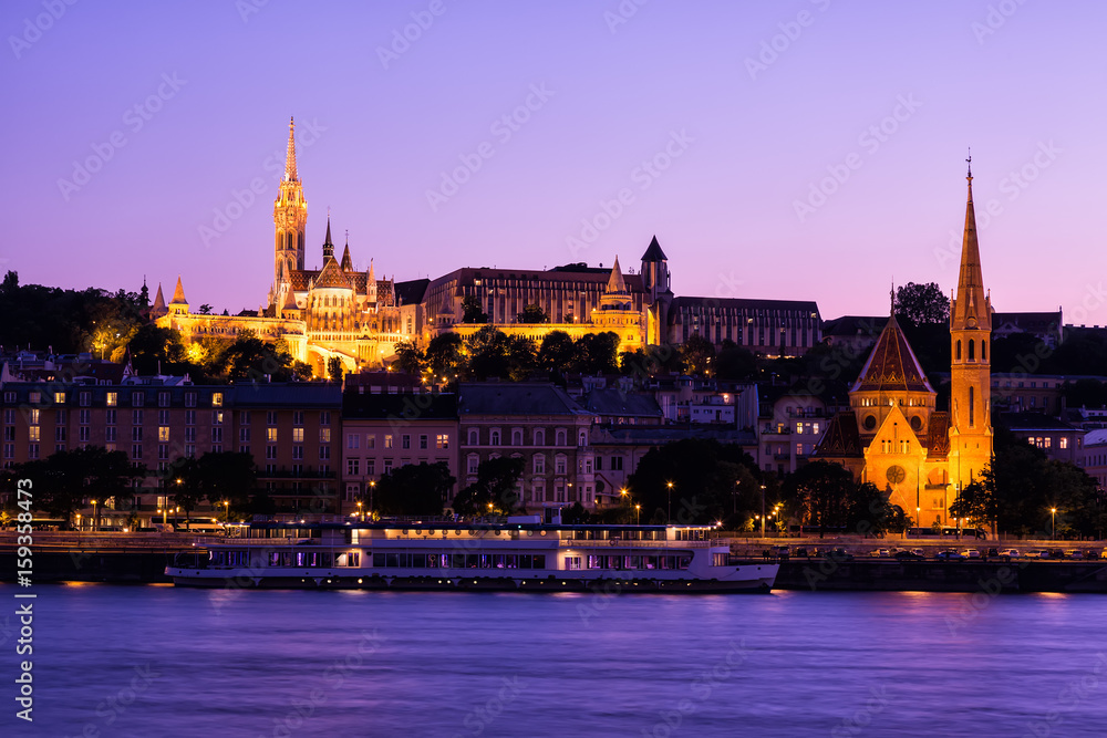 The gothical Matthias church, in the Buda district near the Fisherman's Bastion at sunset with sightseeing ship