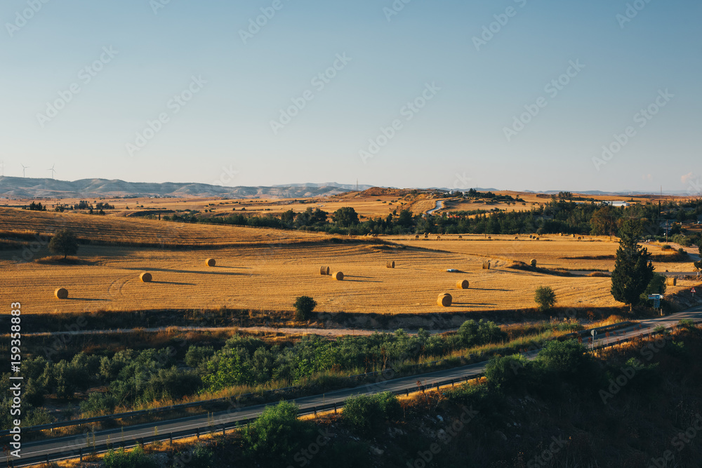 Golden sunset over farm field with hay bales