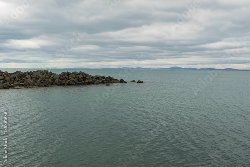 Cloudy day at sea with rocks and calm water