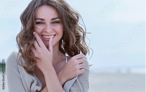 Woman face Portrait on the beach. Happy beautiful curly-haired girl close-up, the wind fluttering hair. Spring portrait on the beach. Young pretty girl. Young smiling outdoors portrait. Close. ocean.