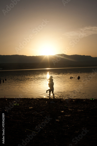 A couple playing on the shore at sunset, in Zrce beach, Croatia