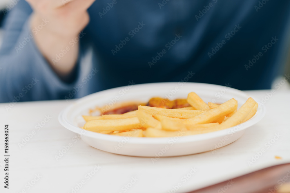hands of a man eating a currywurst with a fries outdoor hands of a man eating a currywurst with a fries outdoor