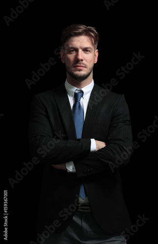 Handsome business man isolated on black with arms crossed © ASDF
