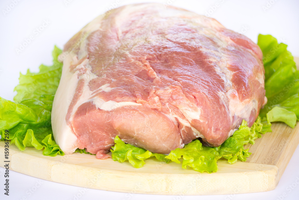 Raw cervical carbonate of pork on cutting board with leaves of green salad, isolated on white background Raw cervical carbonate of pork on cutting board with leaves of green salad, isolated on white background