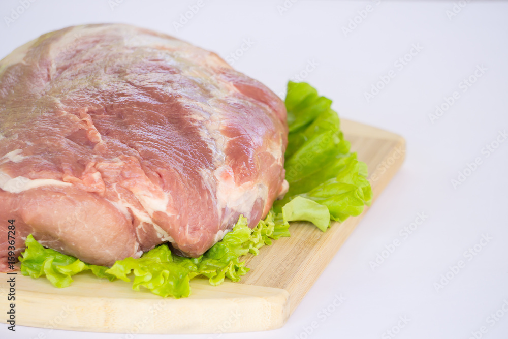Raw cervical carbonate of pork on cutting board with leaves of green salad, isolated on white background Raw cervical carbonate of pork on cutting board with leaves of green salad, isolated on white background