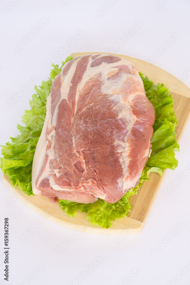 Raw cervical carbonate of pork on cutting board with leaves of green salad, isolated on white background Raw cervical carbonate of pork on cutting board with leaves of green salad, isolated on white background