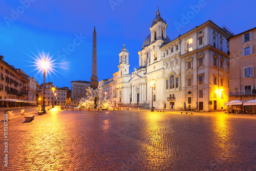 Fountain of the Four Rivers with an Egyptian obelisk and Sant Agnese Church on the famous Piazza Navona Square at night, Rome, Italy.