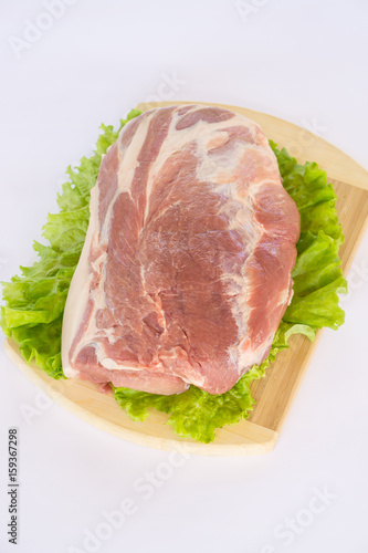 Raw cervical carbonate of pork on cutting board with leaves of green salad, isolated on white background