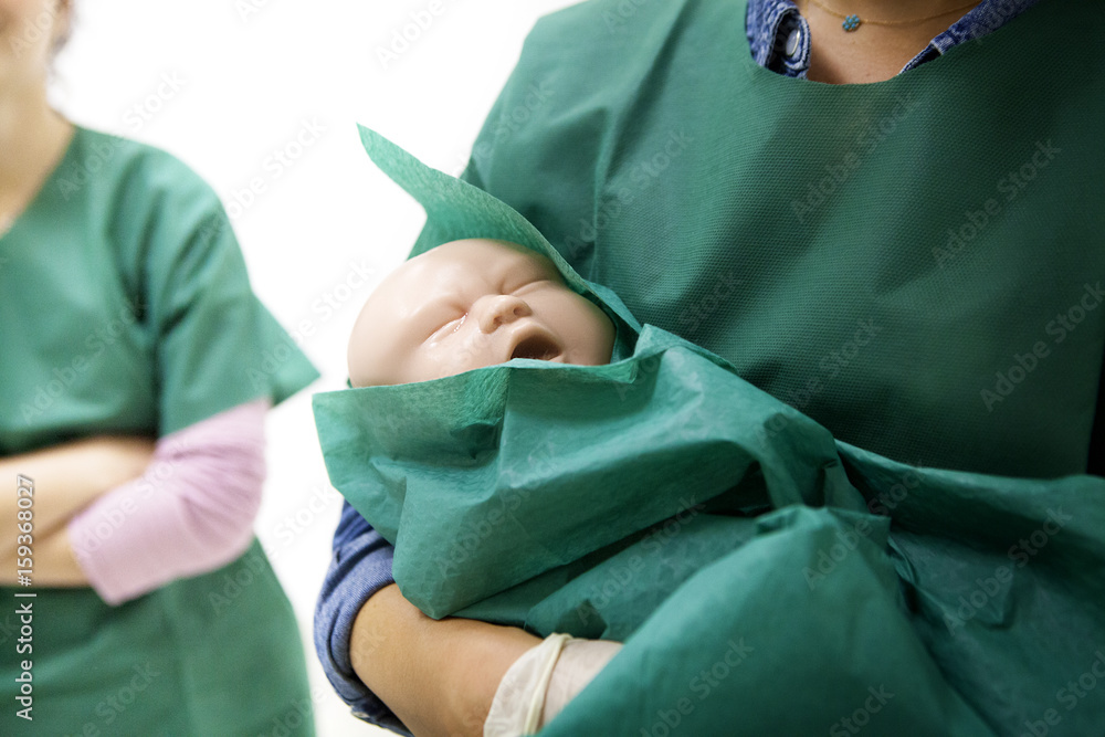 Midwife carrying mannequin in arms while training Midwife carrying mannequin in arms while training