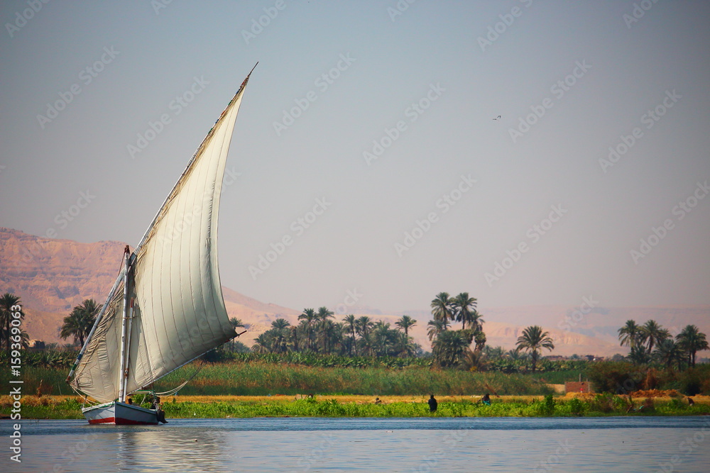 View of feluka boat sailing in the Nile river close to Luxor harbor, Egypt. View of feluka boat sailing in the Nile river close to Luxor harbor, Egypt.