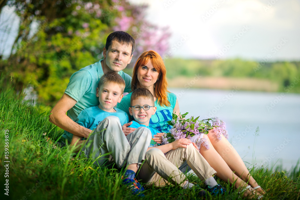 happy family on walk in the park, sit on the river bank with a bouquet of flowers in hands