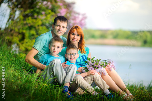 happy family on walk in the park, sit on the river bank with a bouquet of flowers in hands © Tortuga