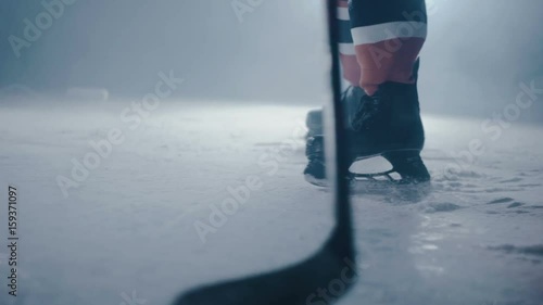 Hockey player hits the puck with a stick on ice close-up