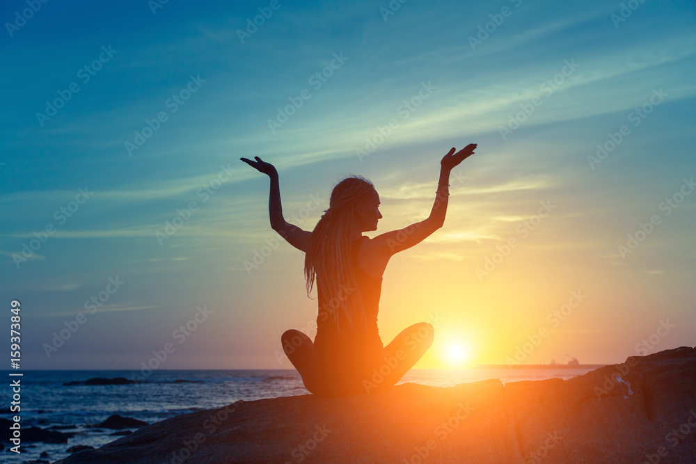 Fototapeta premium Yoga silhouette. Meditation woman on the ocean during amazing sunset.