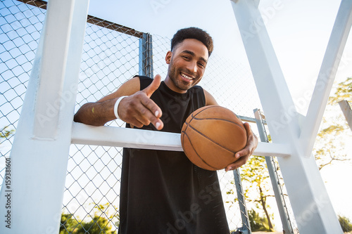 Handsome Strong man is holding ball on the basketball court.attractive,laugh,sport games,street ball,black,sport outfit,casual wear,black clothes