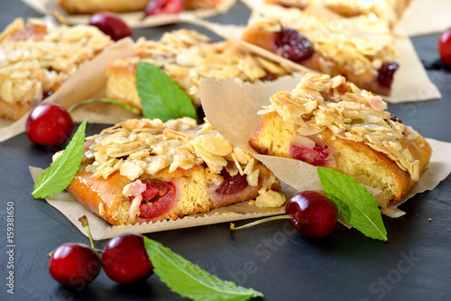 Geschnittener Kirsch-Hefekuchen mit Florentiner-Knusper-Karamel (Blechkuchen,  österr. Germkuchen mit frischen Kirschen und Honigmandeln) -  Yeast cake with fresh cherries  and crunchy almond caramel photo