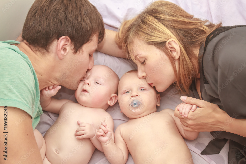 indoor portrait of young happy smiling mother and father with twin babies at home indoor portrait of young happy smiling mother and father with twin babies at home
