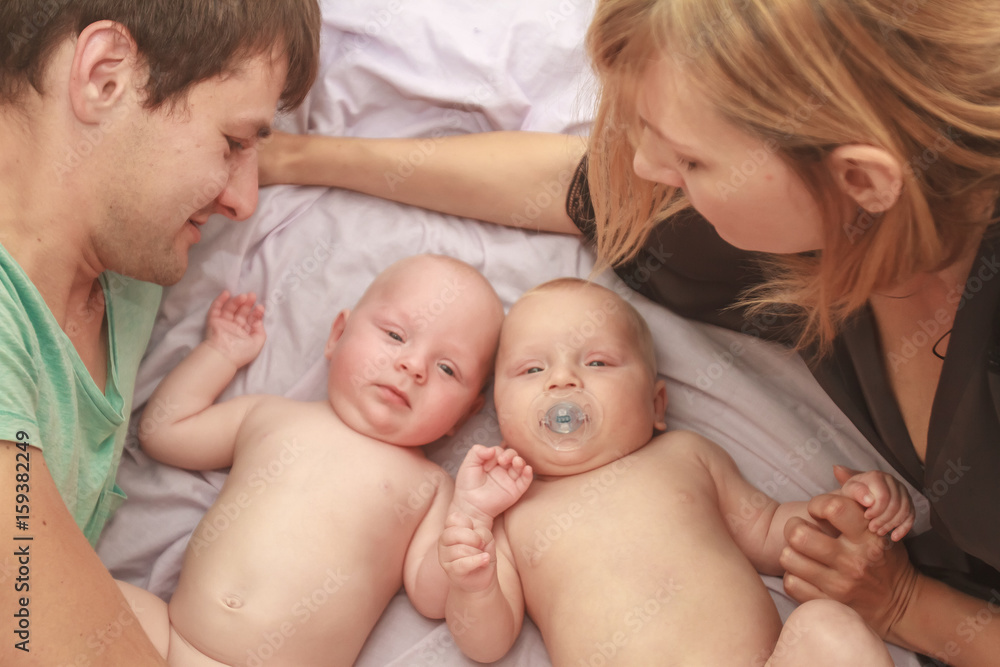 indoor portrait of young happy smiling mother and father with twin babies at home indoor portrait of young happy smiling mother and father with twin babies at home